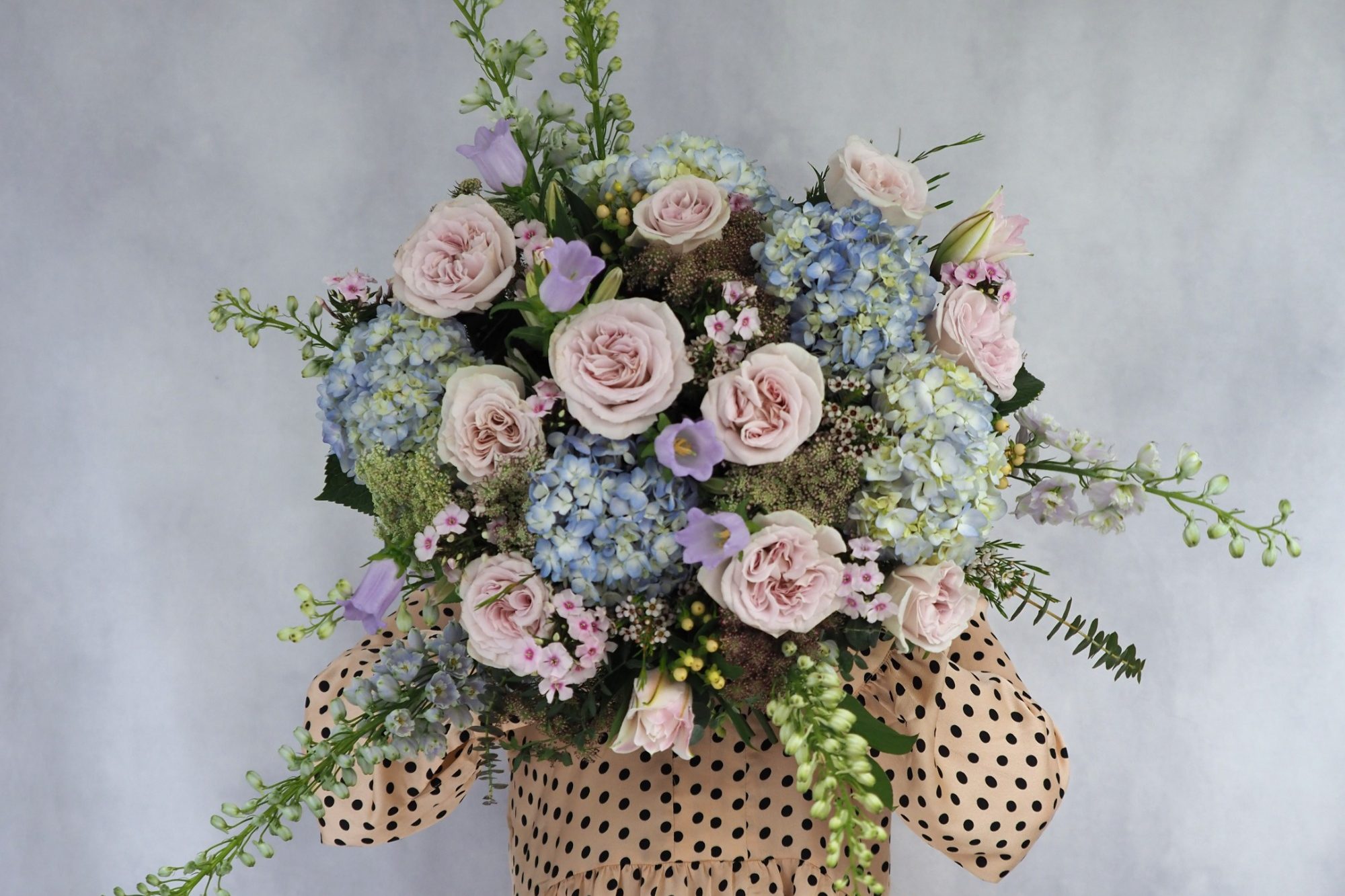 Luxurious domed and structured bouquet containing scented lilac garden roses, pale blue hydrangeas and complimenting pastel flowers. Beautifully arranged and hand tied. 